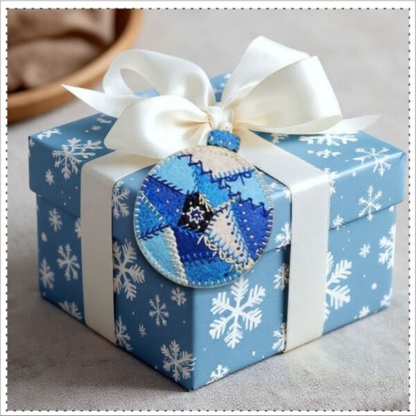 Blue Christmas Hand Embroidered Ornament adorning a gift box
