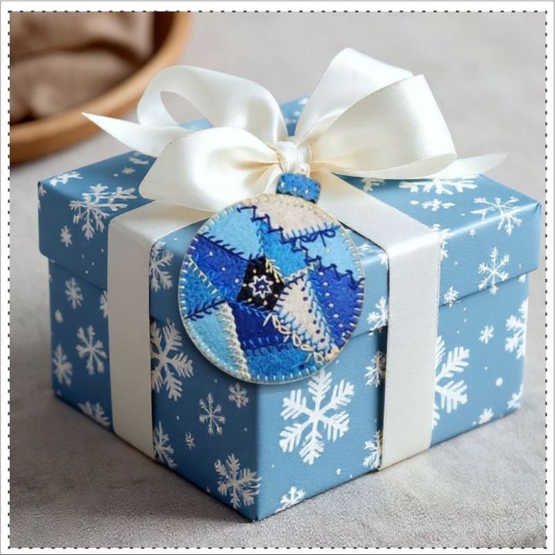 Blue Christmas Hand Embroidered Ornament adorning a gift box
